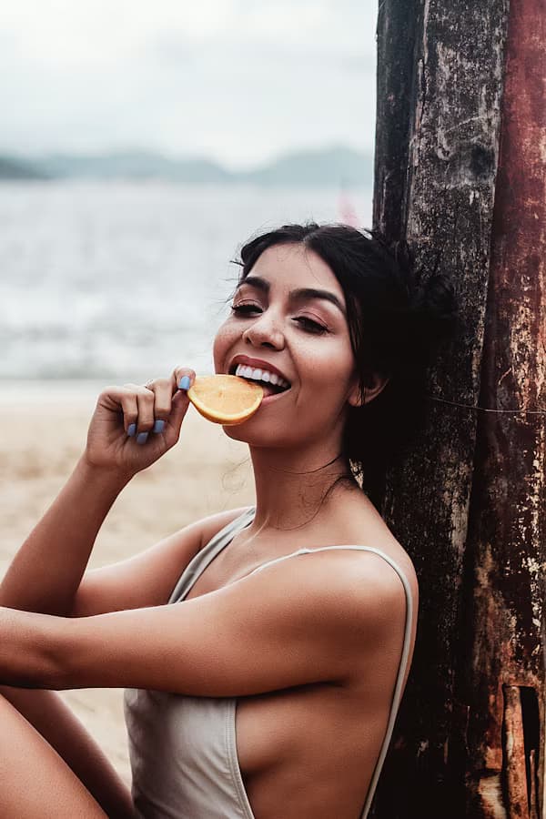 Woman enjoying an orange beside the water